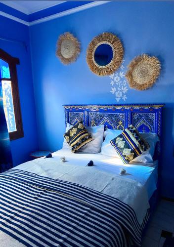 a blue bedroom with a bed with blue walls and mirrors at CASA AMRANi in Chefchaouene