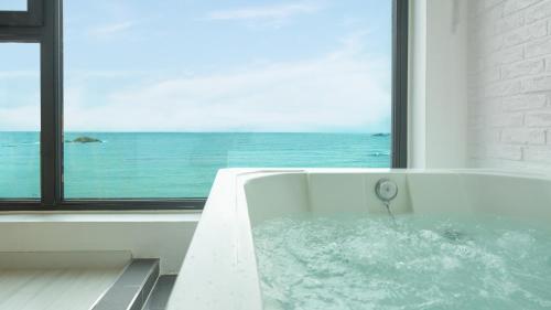 a bath tub with a view of the ocean at Goseong Littlesquare Oceanview Pension in Goseong