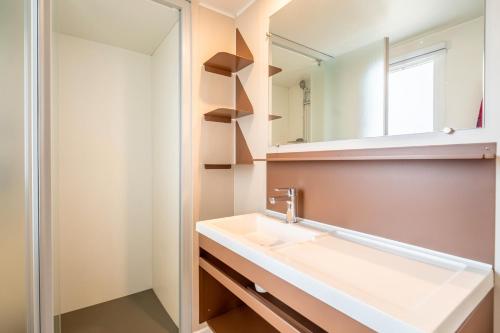 een badkamer met een wastafel en een spiegel bij Mobilhome au Camping La Yole in Vendres-Plage
