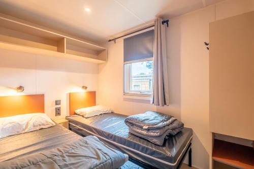 twee bedden in een kamer met een raam bij Mobilhome au Camping La Yole in Vendres-Plage