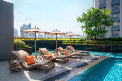 a group of chairs and umbrellas next to a swimming pool at Hotel Nikko Bangkok in Bangkok