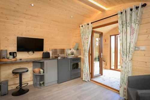 a log cabin with a kitchen and a television at Luxury Glamping Pod - Garthside Farm Holidays in Brampton