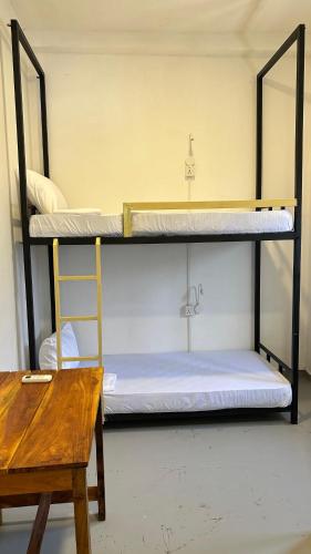 two bunk beds in a room with a wooden table at Wake N Flow, Ahangama - Kabalana Beach in Ahangama