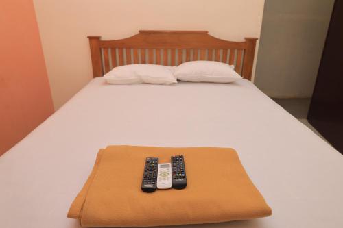 two remote controls are sitting on a bed at Magesh Residency in Jāmb