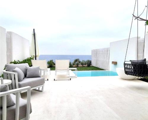 a patio with a couch and chairs and a pool at Escape by Orchid in Batroûn