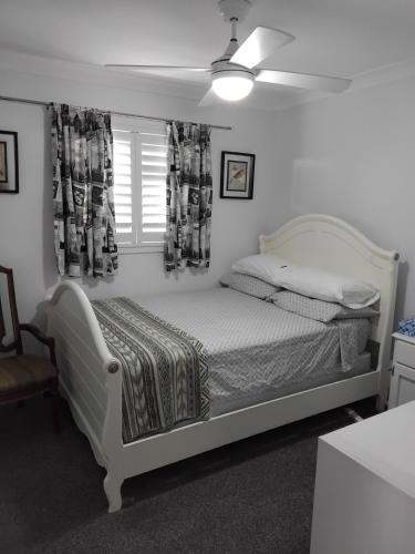 a bedroom with a white bed and a window at Holiday house in Nelson Bay