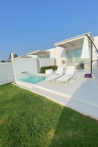 a patio with white chairs and an umbrella at Escape by Orchid in Batroûn