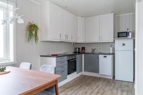 a kitchen with white cabinets and a wooden table at Ure Lodge in Sennesvik