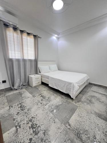 a white bedroom with a bed and a window at Cosy Villa with Pool Toubab Dialaw Senegal in Toubab Dialaw