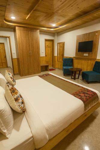 a bedroom with a large bed and a tv at Apple Flower Himalayan Heights - Luxury Stay with Mountain Views, Parking & Garden in Manāli