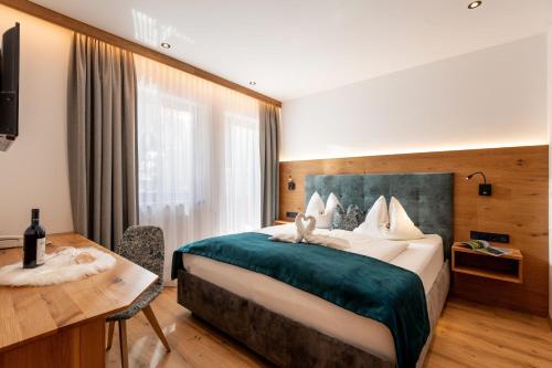 a hotel room with a large bed and a desk at Hotel ALPINJUWEL 3-Sterne Superior in Gerlos