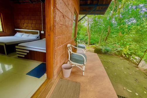 a room with a bed and a chair on a patio at Edgestay in Mudigere