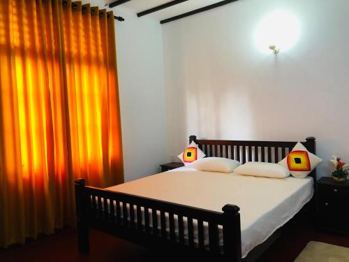 a bedroom with a bed and an orange curtain at Niskalanka Villa in Ahungalla