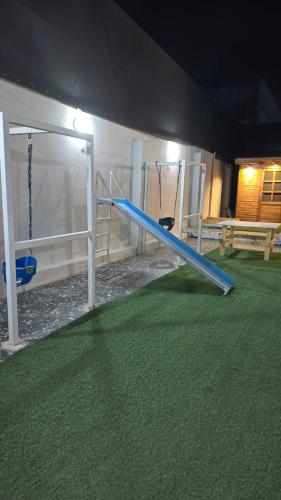 a playground with two swings and a blue slide at شاليهات روزڤيو الريفيه Roseview chalets in Taif