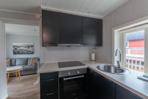 a kitchen with black cabinets and a sink at Ure Lodge in Sennesvik