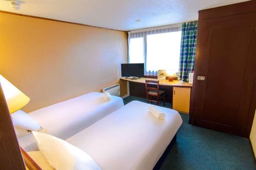 a hotel room with two beds and a desk and a table at The Runmere Hotel, Part of AG Collection in Runcorn