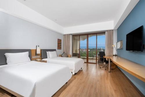 a hotel room with two beds and a desk with a television at Holiday Inn Express Haikou West Coast by IHG in Haikou