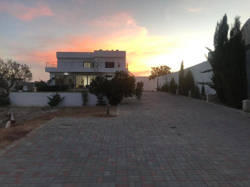 a building with a sunset in the background at Sea View Villa, 5 min from Beach and City Center Chott Mariem in Akouda