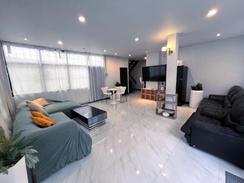 a living room with a couch and a television at Single house 4BR parking and kitchen in Sukhumvit49-1 in Bangkok