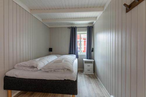 a bedroom with a bed with white sheets and a window at Ure Lodge in Sennesvik
