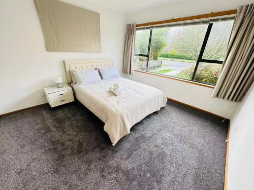 a bedroom with a bed and a large window at Cosy 3 Bedrooms House Beside City Centre in Hamilton