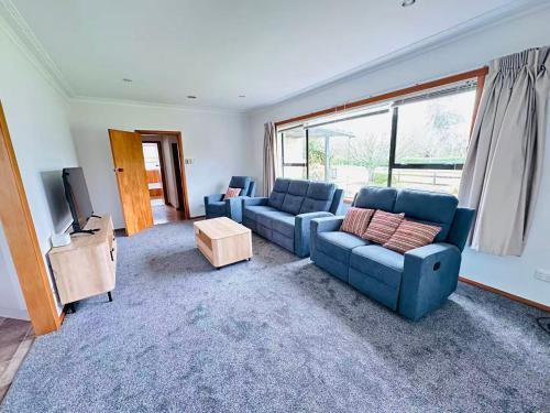 a living room with two blue couches and a television at Cosy 3 Bedrooms House Beside City Centre in Hamilton