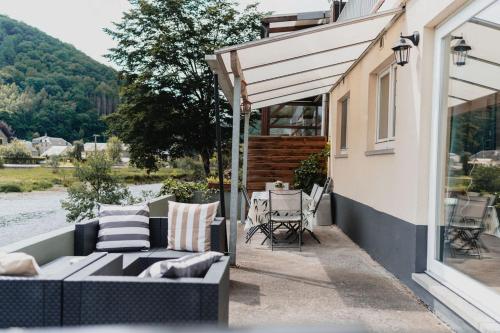 a patio with a couch and a table and chairs at Appartementen met zicht op de rivier de Semois en eigen balkon in Vresse-sur-Semois