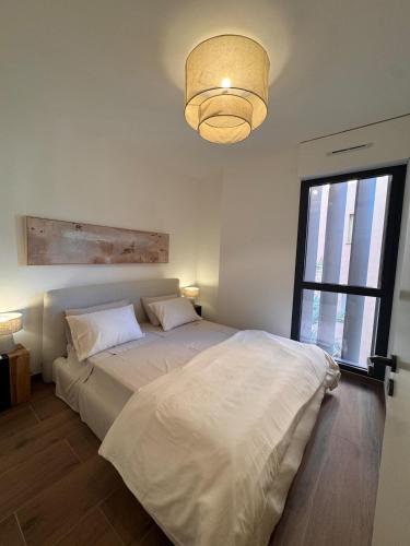 a bedroom with a white bed and a window at Stylish 2BR Monaco Border Flat, Terrace & Parking in Beausoleil