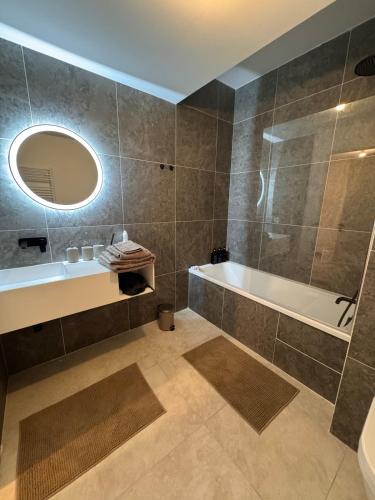a bathroom with a tub and a sink and a mirror at Stylish 2BR Monaco Border Flat, Terrace & Parking in Beausoleil