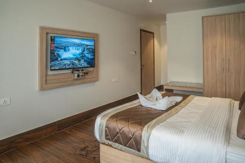 a bedroom with a bed and a tv on the wall at Hotel Arjay Valley, Pure Veg Luxury Hotel in Darjeeling