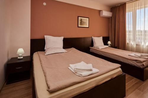 a bedroom with two beds with white towels on them at Хотел "Божур" in Mineralni Bani