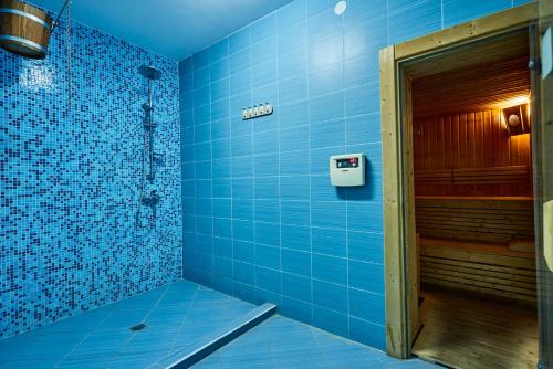 a blue bathroom with a shower with blue tiles at Хотел "Божур" in Mineralni Bani