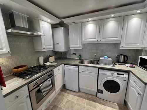 a kitchen with white cabinets and a washing machine at Sea View in Shanklin