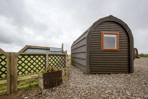 a small black shed next to a wooden fence at Unit 4 - Skiddaw View Camping Pod in Carlisle