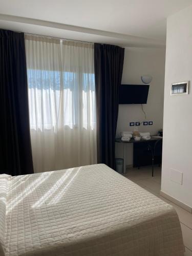 a bedroom with a bed and a window with a desk at Hotel Ulisse in Marina Romea