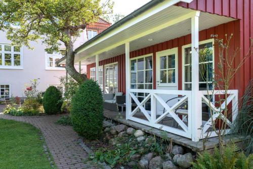 a red house with a white door and a porch at Lütt Drosselhörn 2 in Laboe