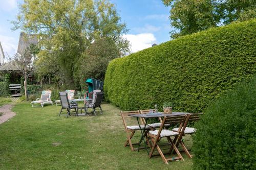 a table and chairs in a yard with a hedge at Lütt Drosselhörn 1 in Laboe
