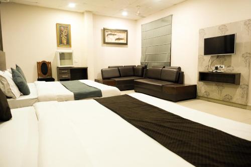 a hotel room with two beds and a couch at Hotel De Agya Paradise in Ludhiana