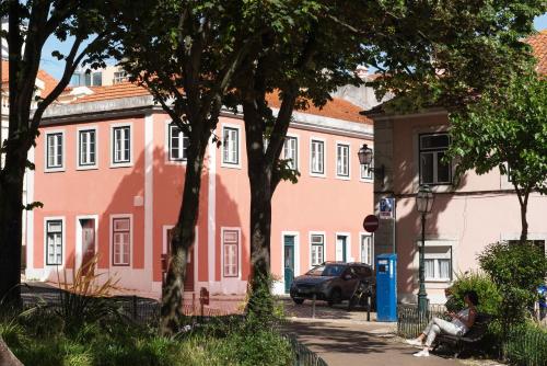 a woman sitting on a bench in front of a pink building at CASA AMORA Studio Apartments in Lisbon