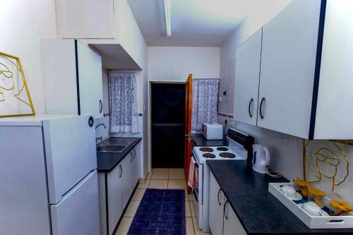 a kitchen with white appliances and black counter tops at River flow apartment in Manzini