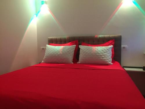 a bedroom with a red bed with two red pillows at River Side Apartment in Prizren