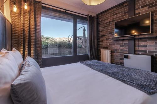 ein Schlafzimmer mit einem großen Bett und einem großen Fenster in der Unterkunft Le Saint Bernard - T2 Terrasse Vue Mont Joli 42m2 in Saint-Gervais-les-Bains