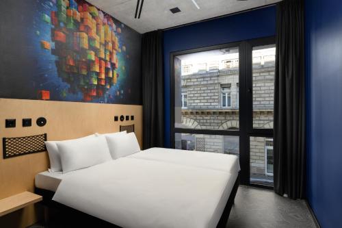 a bedroom with a white bed and a painting on the wall at JO&JOE Budapest in Budapest