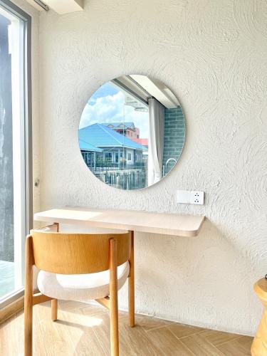 a mirror on a wall with a table and a chair at Baan Tah On The Sea in Bang Sare