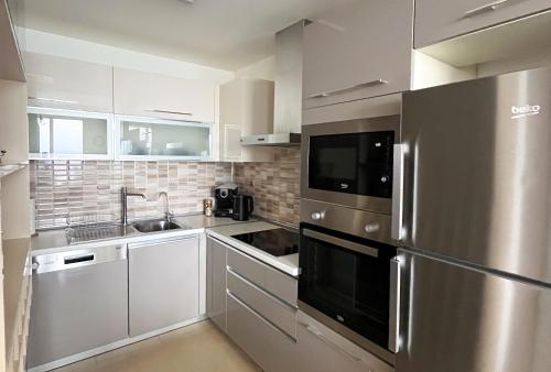 a kitchen with white cabinets and a stainless steel refrigerator at BlueSky 31 in Skopje