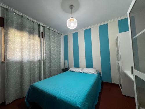ein kleines Schlafzimmer mit einem blauen Bett und gestreiften Wänden in der Unterkunft Casa da Areia Branca in Bolembre de Baixo