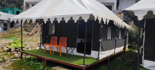 a black and white tent with chairs in it at Chopta Rock Hill Camp in Chopta