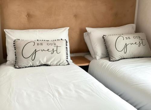 two beds with white pillows with the words be our guest at 2-Bed Lodge Sleeps 4 Free Parking Hot tub in Preston