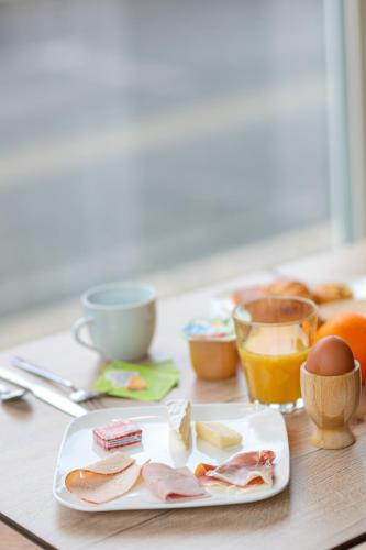 a table with a plate of food with eggs and cheese at Ostal Pau Universite - Sure Hotel Collection by Best Western in Pau