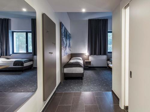 a hotel room with two beds and a mirror at B&B Hotel München-Olympiapark in Munich